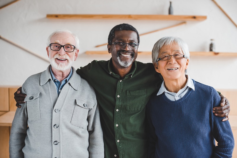 Group,Of,Multiethnic,Senior,Friends,Embracing,And,Looking,At,Camera